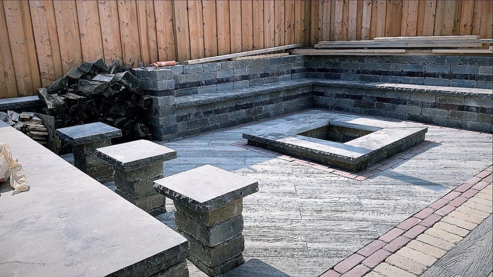 Backyard hardscape with stone bench seating, fire pit, and paver patio